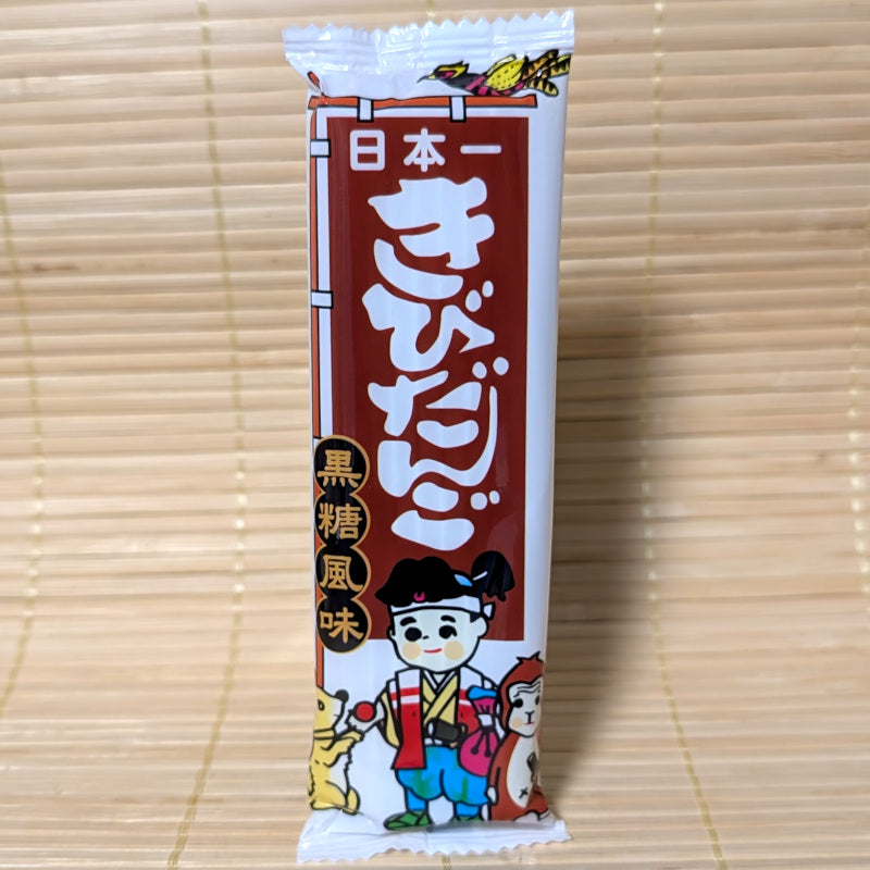 Japanese Kibi Dango Kokuto dagashi candy package with cartoon Momotaro character all displayed on a tatami surface.