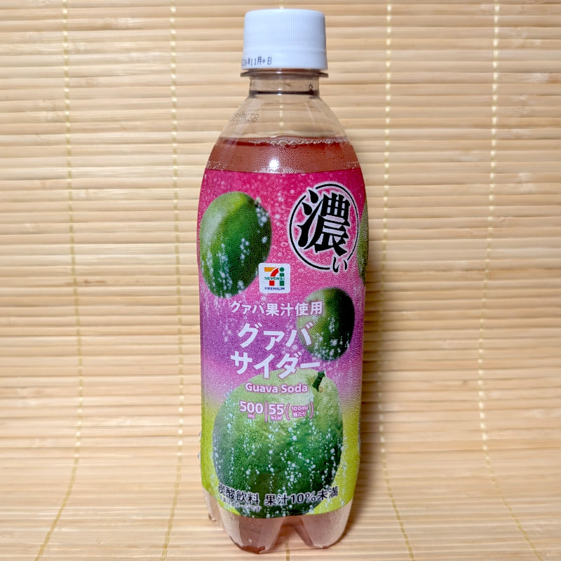 A 500ml clear plastic bottle of 7-Eleven Premium Guava Cider featuring a vibrant pink and green label with fresh guava fruit graphics on a bamboo mat background.