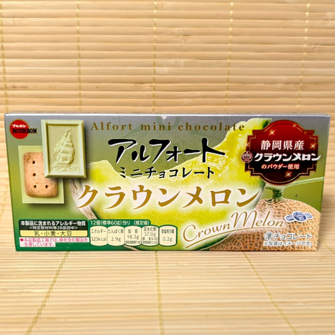 A green and silver box of Bourbon Alfort Mini Chocolate Crown Melon featuring a sliced green melon and a sample biscuit showing the sail boat design, on a tatami background.