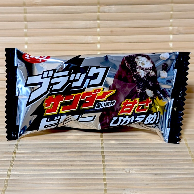 A silver and black wrapper of Black Thunder Mini Bitter Chocolate Bar on a bamboo mat background.