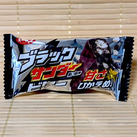 A silver and black wrapper of Black Thunder Mini Bitter Chocolate Bar on a bamboo mat background.
