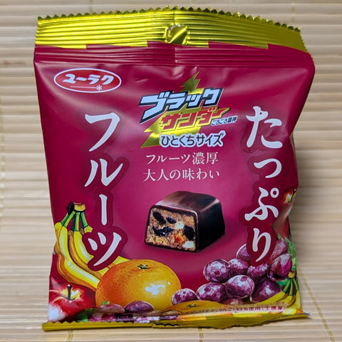 A pack of Black Thunder Fruit Mix chocolate displayed on a tatami background.