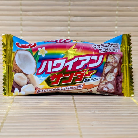 A bright rainbow and blue wrapper of Hawaiian Black Thunder chocolate bar featuring fresh coconut and macadamia nut graphics on a tatami background.