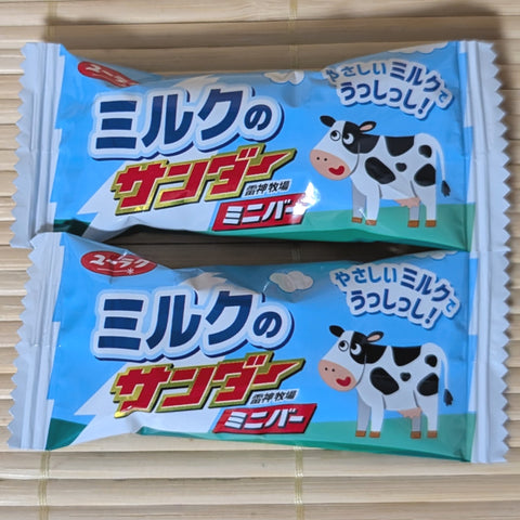 Two packages of Black Thunder White milk candy with cow illustrations on it. Displayed on a wooden surface.