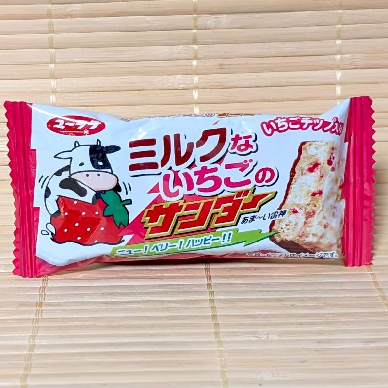 A white and pink wrapper of Black Thunder Mini Strawberry Milk Chocolate Bar featuring a cartoon cow hugging a strawberry on a bamboo background.