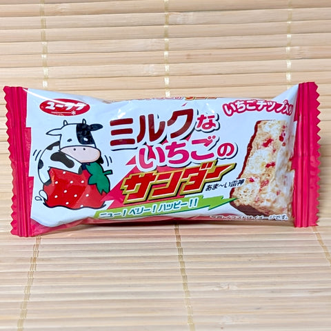 A white and pink wrapper of Black Thunder Mini Strawberry Milk Chocolate Bar featuring a cartoon cow hugging a strawberry on a bamboo background.