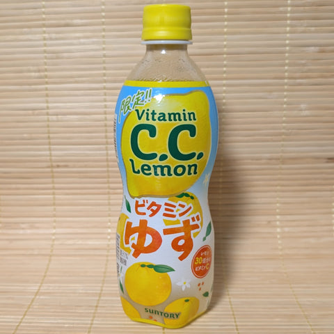 A 500ml plastic bottle of limited edition Suntory C.C. Lemon Vitamin Yuzu soda featuring a bright blue and yellow label with whole yuzu fruit illustrations on a tatami mat background.