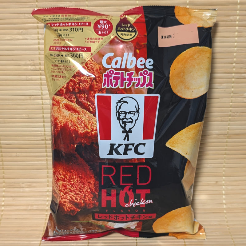 A black and gold 62g bag of Calbee KFC Red Hot Chicken chips showing the classic Colonel Sanders logo and spicy fried chicken pieces on a tatami background.