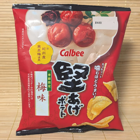 A red bag of Calbee Kata-Age potato chips featuring an illustration of three whole red ume plums and crunchy kettle-style chips. Displayed on a tatami surface.