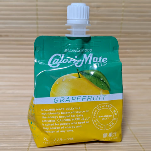 A green and yellow squeezable pouch of Calorie Mate Jelly Grapefruit featuring a whole yellow grapefruit illustration. Displayed on a tatami background.