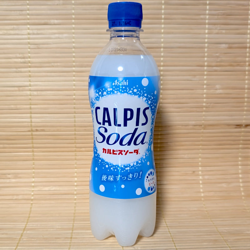 A 500ml PET bottle of Asahi Calpis Soda displaying blue and white bubble graphics on a bamboo mat background.