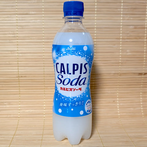 A 500ml PET bottle of Asahi Calpis Soda displaying blue and white bubble graphics on a bamboo mat background.