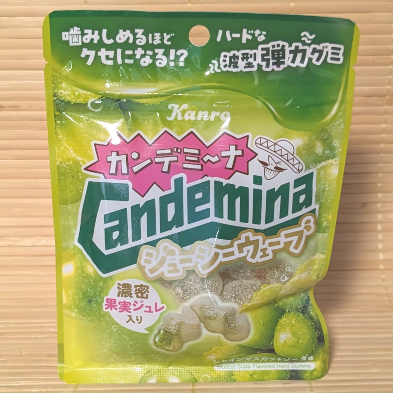 A bright green 66g pouch of Candemina Juicy Wave Muscat Soda gummies on a bamboo mat.