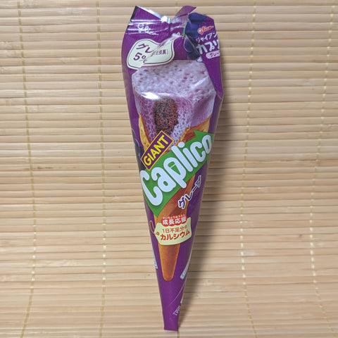 A vibrant purple foil-wrapped Glico Giant Caplico Grape chocolate cone on a natural bamboo mat background.