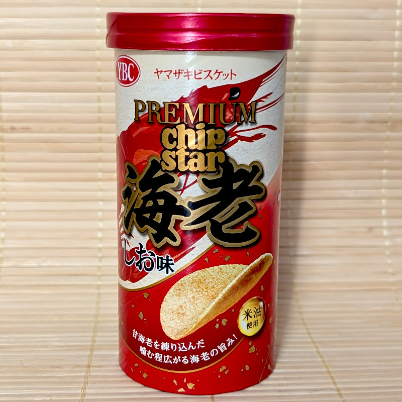 A red and gold 45g cylinder tube of YBC Premium Chip Star Ebi Shio chips showing a large shrimp illustration, gold lettering, and a potato chip on a bamboo mat background.