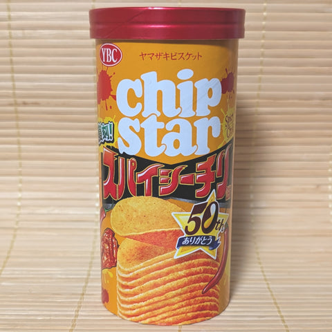 An orange and red canister of YBC Chip Star Spicy Chili chips with a 50th-anniversary logo, photographed on a traditional Japanese tatami background.