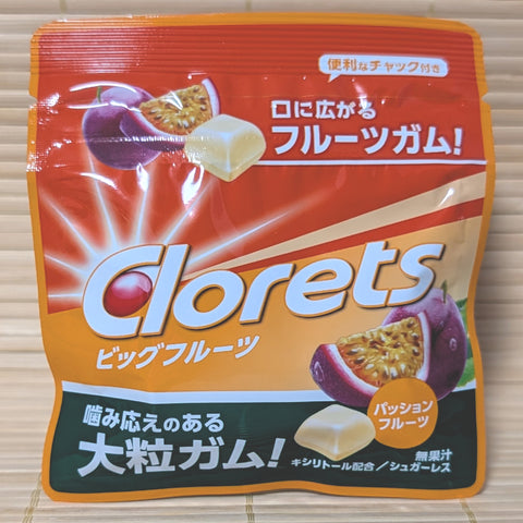 An orange and red resealable pouch of Clorets Big Fruit gum featuring passionfruit illustrations and large white gum pieces.