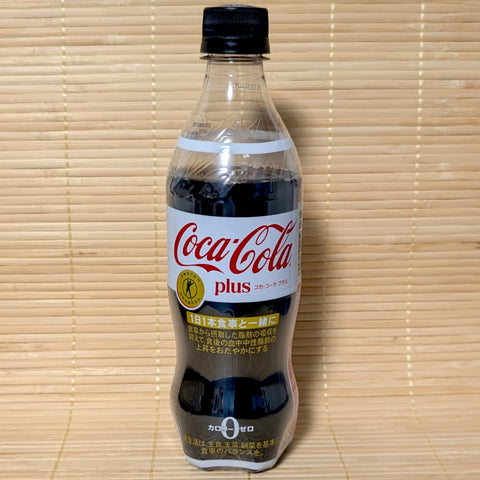 A white label 470ml PET bottle of Japanese Coca-Cola Plus Tokuho functional soda on a bamboo mat.