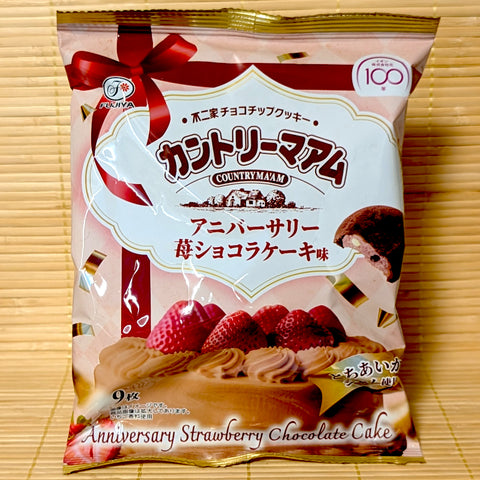 A 90g bag of Fujiya Country Maam Anniversary Strawberry Chocolate Cake cookies celebrating Aeon's 100th anniversary, resting on a bamboo mat.