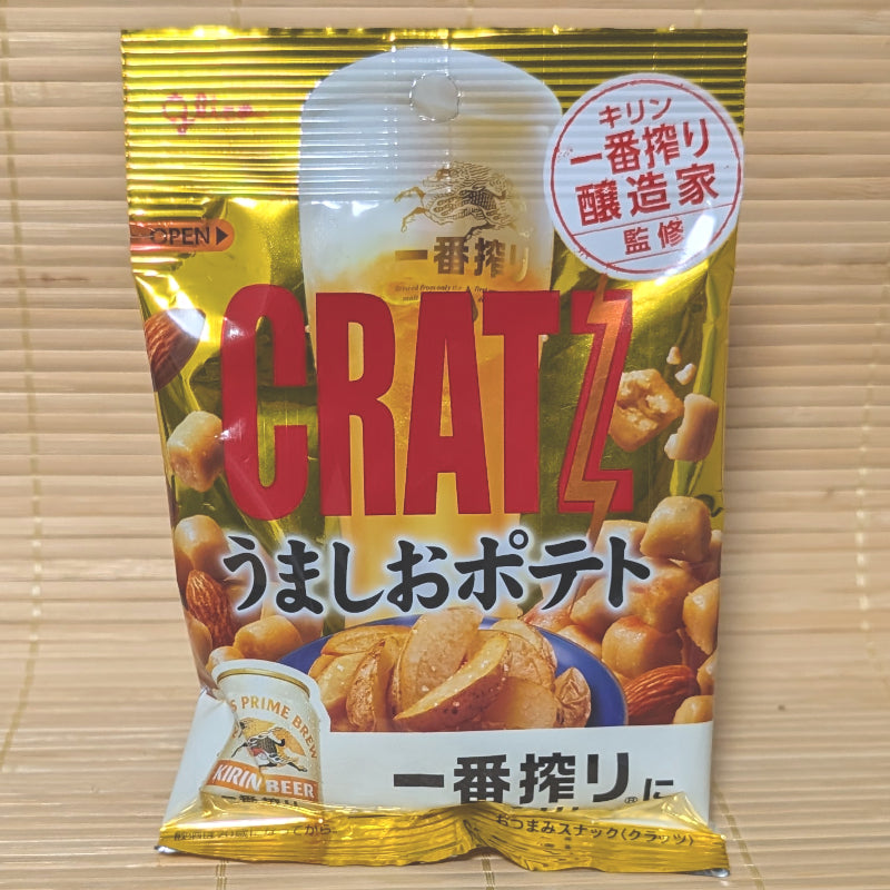 A metallic gold pouch of Glico Cratz Umashio Potato pretzel bits with whole roasted almonds on a tatami background.