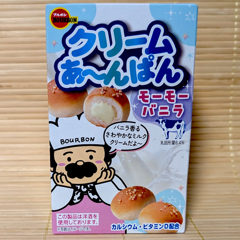 A light blue and pink box of Bourbon Cream Anpan vanilla cookies showing an anchor graphic, a cartoon chef, a spotted cow, and mini bread buns on a tatami background.