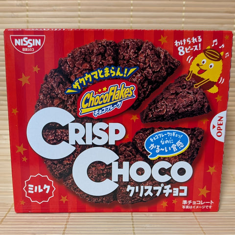 A bright red box of Nissin Cisco Crisp Choco showing a pre-sliced wheel of chocolate-coated cornflakes and a cute yellow mascot on a tatami background.