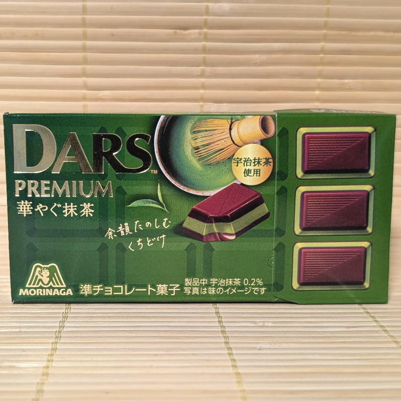 A dark green box of Morinaga DARS Premium Brilliant Matcha chocolate featuring 12 pieces and a matcha whisk illustration. Displayed on a tatami background.