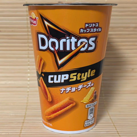 A bright orange Doritos Cup Style container featuring S-curled corn sticks and a cheese wedge graphic, photographed on a traditional Japanese tatami background.