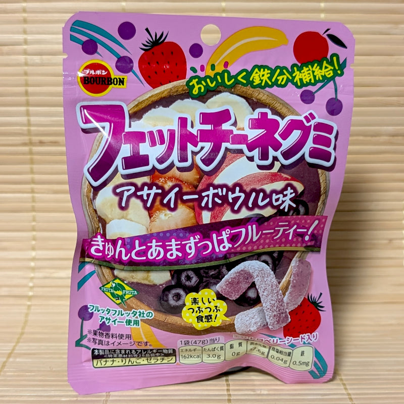 A purple and pink resealable bag of Fettuccine Gummy featuring an acai bowl with bananas, strawberries, and blueberries. Displayed on a tatami background.