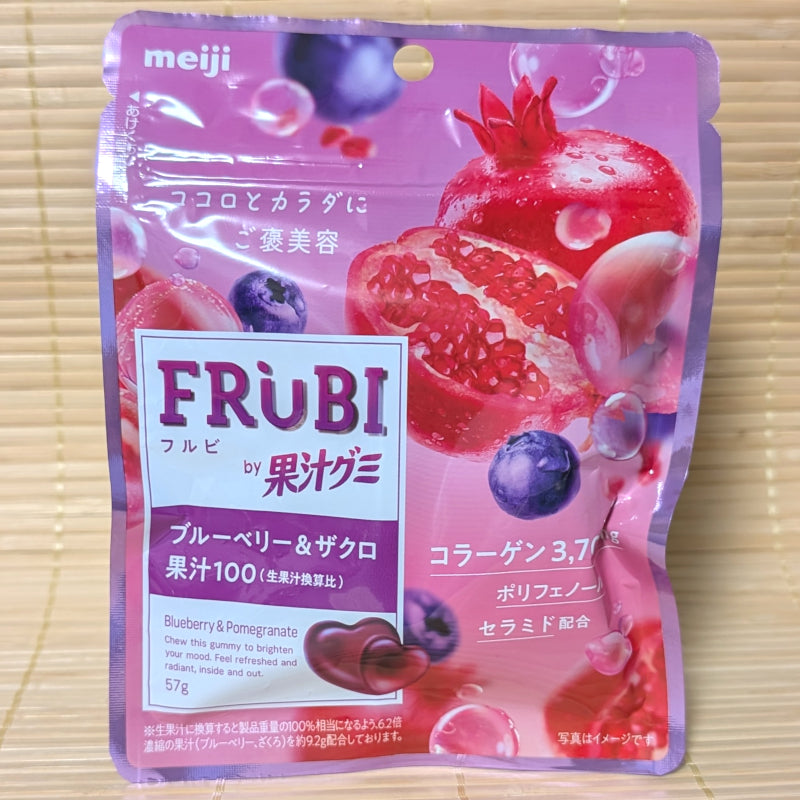 A purple resealable pouch of Meiji FRUBI gummies featuring fresh pomegranates, blueberries, and heart-shaped gummy pieces.
