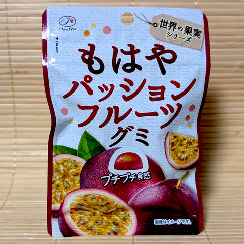 A bright blue and yellow beach themed pouch of Fujiya Mowaya Passion Fruit gummy candy showing a half-moon cut fruit graphic on a tatami background.