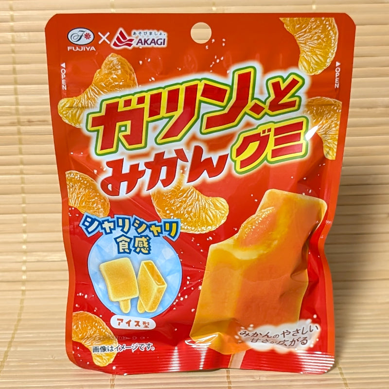 A bright red-orange pouch of Fujiya Gatsun to Mikan Gummy featuring mikan mandarin slice graphics and a mandarin ice bar illustration on a bamboo background.