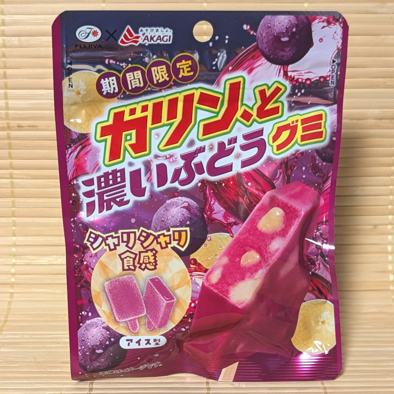 A deep purple 53g pouch of Fujiya Gatsun to Dark Grape Gummy showing popsicle-shaped gummies on a bamboo background.   