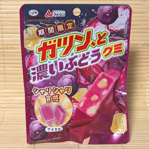 A deep purple 53g pouch of Fujiya Gatsun to Dark Grape Gummy showing popsicle-shaped gummies on a bamboo background.   