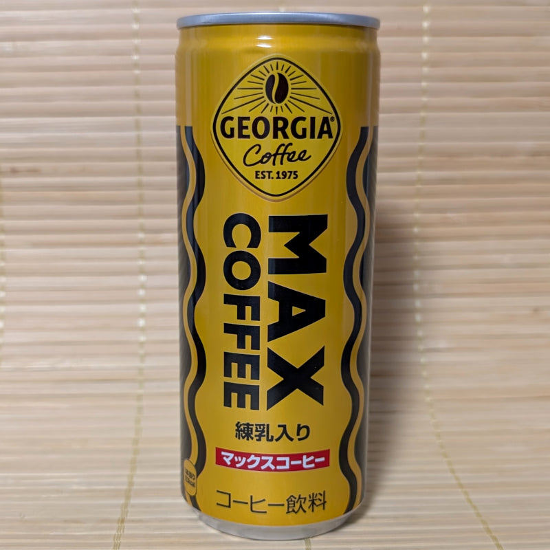 A tall golden-yellow can of Coca-Cola Georgia MAX Coffee with black and orange zig-zag waves on a tatami background.