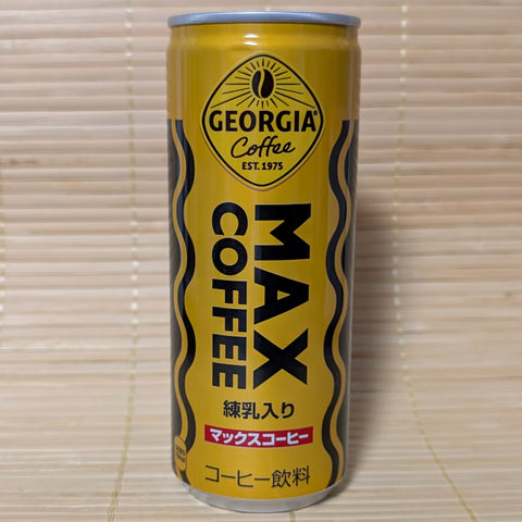 A tall golden-yellow can of Coca-Cola Georgia MAX Coffee with black and orange zig-zag waves on a tatami background.