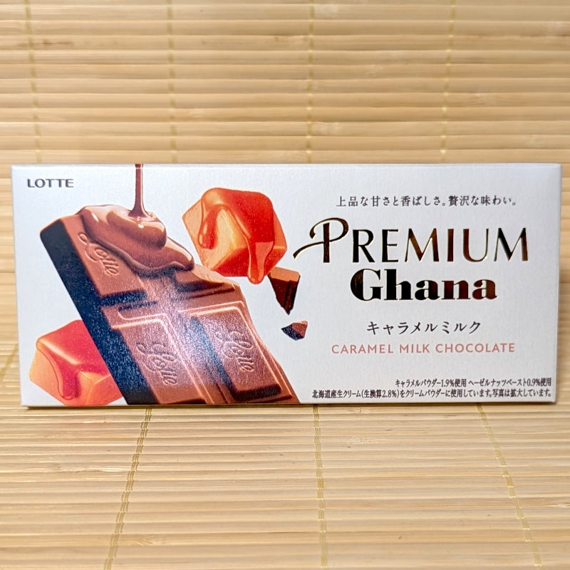 A light beige rectangular box of Lotte Premium Ghana Caramel Milk Chocolate Bar featuring caramel candy graphics on a bamboo background.