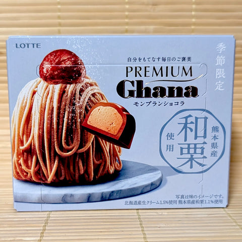 A soft blue box of Lotte Premium Ghana Mont Blanc Chocolat displaying a rich chestnut Mont Blanc dessert graphic on a bamboo mat background.