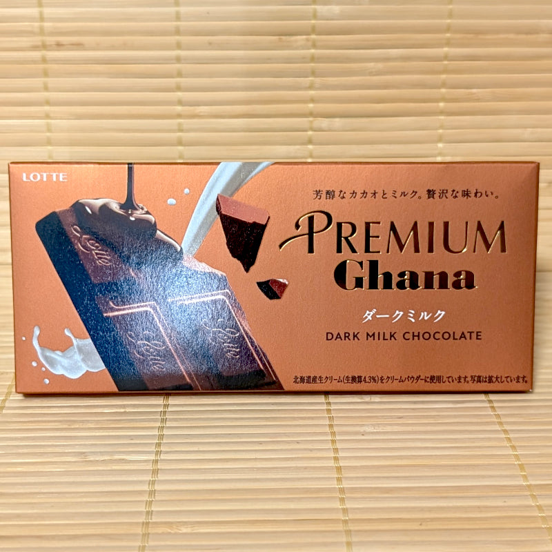 A bronze rectangular box of Lotte Premium Ghana Dark Milk Chocolate Bar featuring splash graphics on a bamboo background.