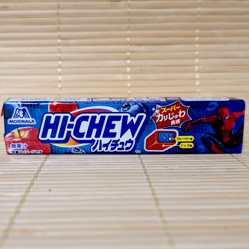 A blue 12-piece stick pack of Morinaga Hi-Chew Duo Blueberry & Cinnamon Apple showing Spider-Man, red apple, blueberries, and a cross-section diagram of the two-tone candy on a bamboo mat background.