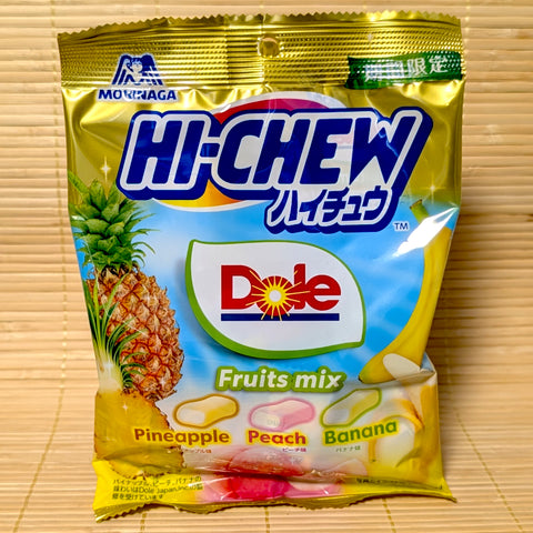 A metallic gold and blue Hi-Chew bag on a tatami background featuring the Dole logo, a pineapple, and a banana.