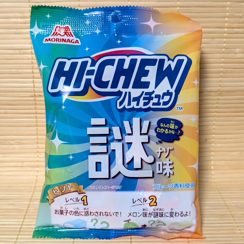 A colorful blue, orange, and green bag of Morinaga Mystery Hi-Chew on a tatami background, featuring "Nazo" mystery text and level-up flavor hints.
