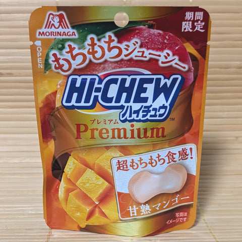 A gold and orange resealable pouch of Hi-Chew Premium Mango showing a cross-section of a soft candy and fresh mango, on a traditional Japanese tatami background.