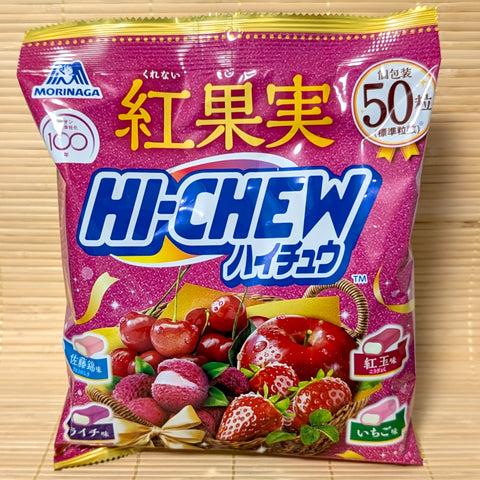 A large magenta bag of Morinaga Hi-Chew Kurenai Fruit featuring 50 pieces of Cherry, Apple, Lychee, and Strawberry flavors. Displayed on a wooden surface.
