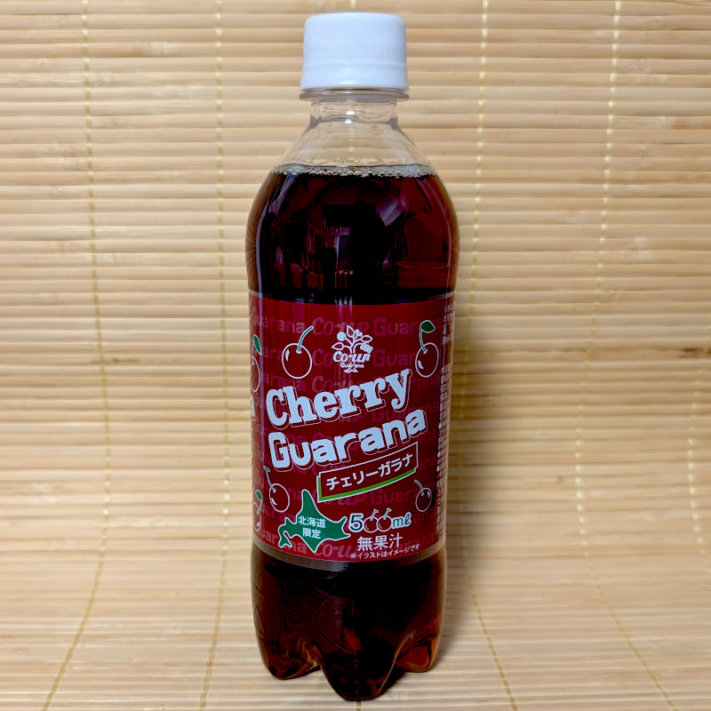 A 500ml bottle of Cherry Guarana soda with a deep red label and cherry graphics, photographed on a traditional Japanese tatami background.