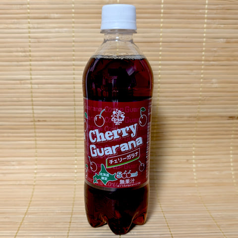 A 500ml bottle of Cherry Guarana soda with a deep red label and cherry graphics, photographed on a traditional Japanese tatami background.