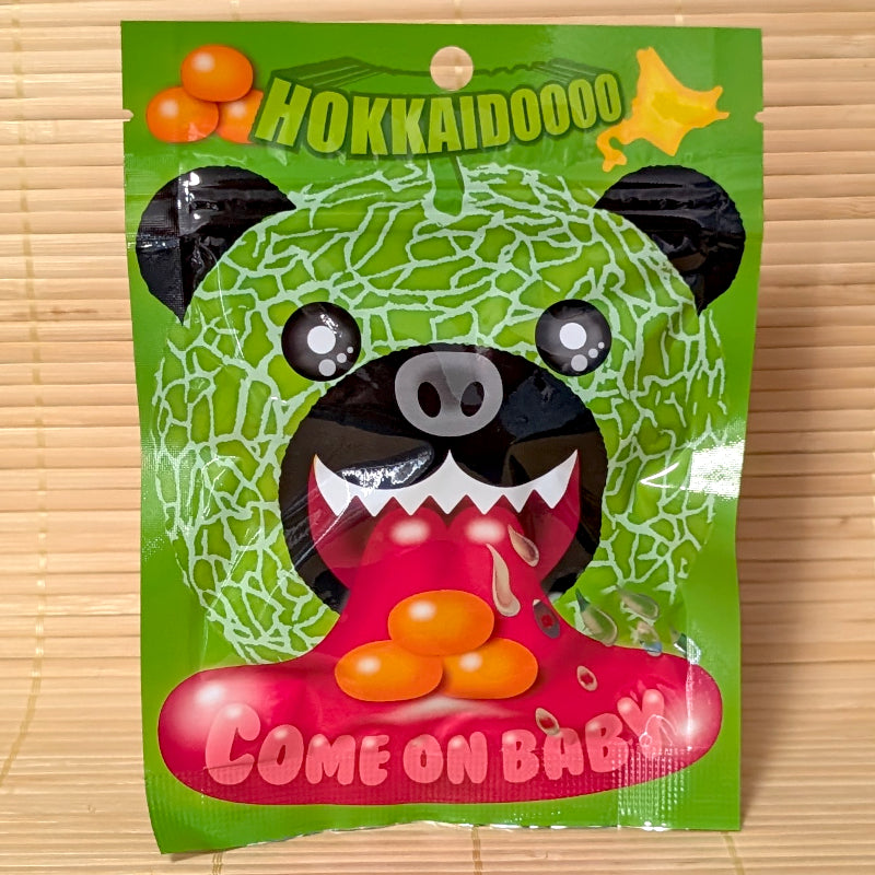Vibrant green 50g pouch of Hokkaido Yubari Melon Bear gummies featuring a black bear wearing a melon mask and "Come On Baby!" slogan.