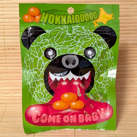 Vibrant green 50g pouch of Hokkaido Yubari Melon Bear gummies featuring a black bear wearing a melon mask and "Come On Baby!" slogan.