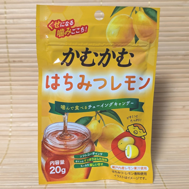 A bright yellow resealable pouch of Kamu Kamu candy featuring a jar of honey and fresh lemons. Displayed on a tatami surface.