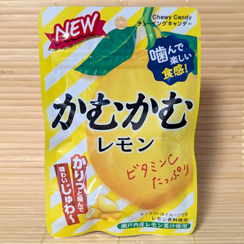 A yellow 30g pouch of Kamu Kamu Lemon Chewy Candy with new packaging layout featuring a large lemon illustration on a bamboo mat.